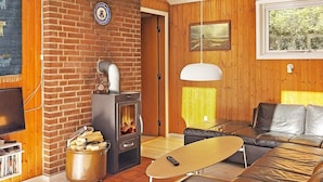 A cozy living room with a brick fireplace, a leather sofa, a coffee table, and a television. - 6 Person Holiday Home in Norre Nebel (Norre Nebel)