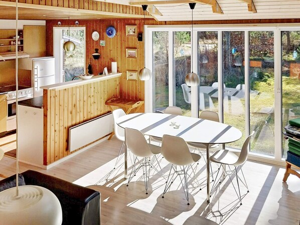 A modern kitchen with a dining area, large windows, and a view of the outdoors.