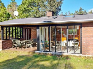 A two-story building with a covered patio area, a brick exterior, and large glass doors leading to an interior space. - 6 Person Holiday Home in Norre Nebel (Norre Nebel)