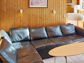 A sectional sofa with a wooden wall and a lamp. - 6 Person Holiday Home in Norre Nebel (Norre Nebel)