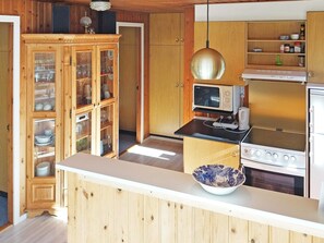 A kitchen with wooden cabinets, a microwave, a stove, and a bowl on the counter. - 6 Person Holiday Home in Norre Nebel (Norre Nebel)