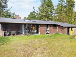 A two-story brick building with a flat roof, a covered patio area with outdoor seating, and a small attached structure. - 6 Person Holiday Home in Norre Nebel (Norre Nebel)