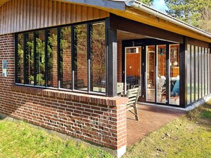 A modern building with large windows, a brick facade, and a covered patio area.
