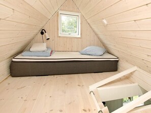A small, triangular wooden room with a single bed, a window, and a ceiling light. - 4 Person Holiday Home in Skagen (Skagen)