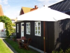 A house with a dark exterior, a white roof, and a small patio with a table and chairs. - 4 Person Holiday Home in Skagen (Skagen)