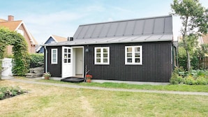 A single-story house with a dark exterior, white-framed windows, and a grey roof. - 4 Person Holiday Home in Skagen (Skagen)