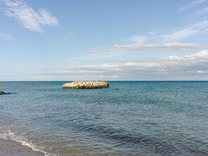 Une mer calme avec une grande formation rocheuse au milieu.
