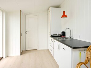 A compact kitchen with a black countertop, a single sink, and a red pendant light. - 4 Person Holiday Home in Skagen (Skagen)