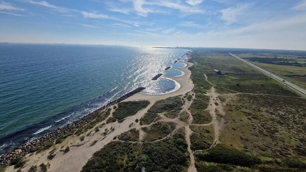 An aerial view of a coastal landscape with a beach, a road, and a distant horizon. - 4 Person Holiday Home in Skagen (Skagen)