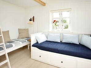 Une chambre avec un lit superposé, un bureau, une lampe et une fenêtre ornée de fleurs.