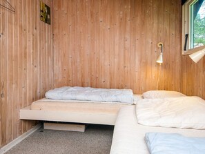 A single bed with a mattress and pillows, a pull-out desk, a wall-mounted light fixture, and a window with a view of greenery. - 4 Person Holiday Home in Oksbol (Oksbol)