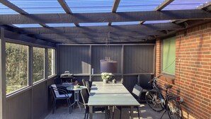 A covered patio with a table and chairs, a hanging light fixture, and a bicycle. - 3 Person Holiday Home in Ansager (Ansager)
