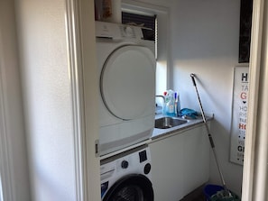 A compact laundry area with a washing machine, a drying rack, and a mopping bucket.