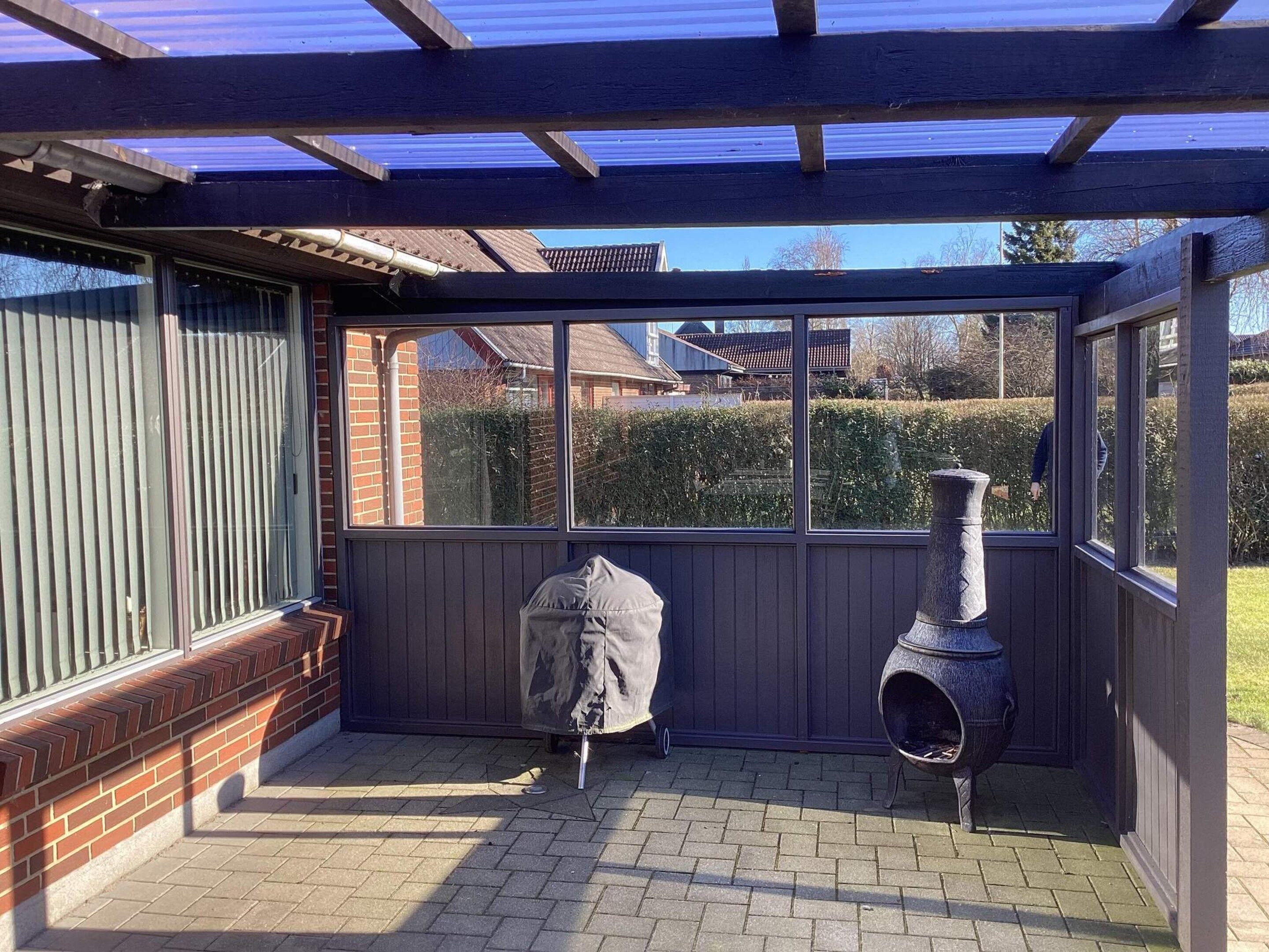Un espacio cubierto con patio, suelo de ladrillo, una parrilla y una chimenea.