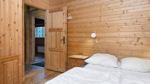 A wooden room with a bed, a nightstand, and a door leading to another room. - 6 Person Holiday Home in Farvang (Farvang)