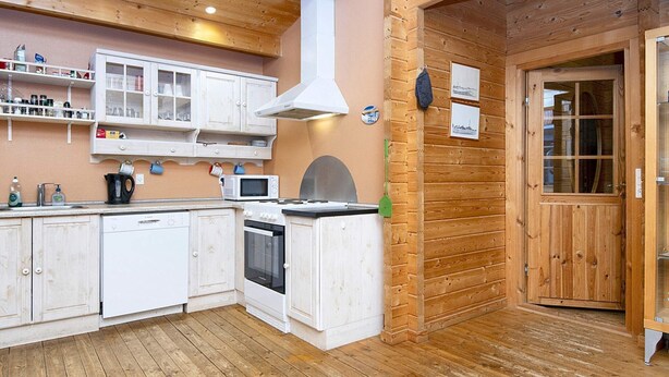 A compact kitchen with white cabinetry, a stove, microwave, and a sink. - 6 Person Holiday Home in Farvang (Farvang)