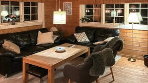 A cozy cabin interior with a wooden interior, two black leather sofas, a wooden coffee table, and a single chair. - 6 Person Holiday Home in Farvang (Farvang)