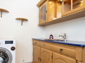 A compact kitchen with wooden cabinets, a built-in washing machine, and a sink with a faucet.