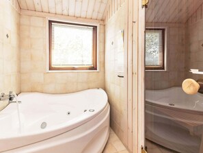 Une salle de bain avec une grande baignoire, une fenêtre et un espace douche.