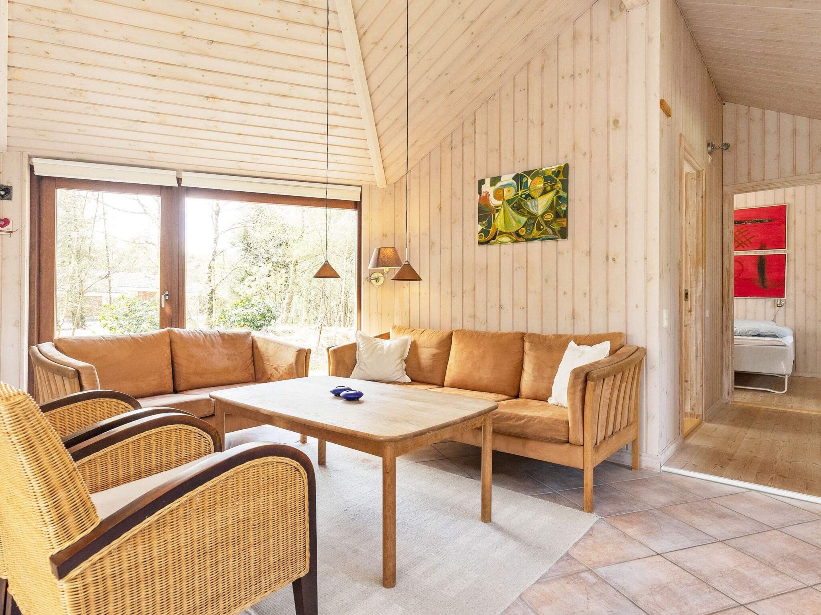 A cozy room with a sofa, chairs, a table, and a painting on the wall.