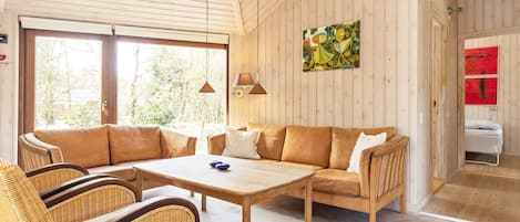 A cozy room with a sofa, chairs, a table, and a painting on the wall.