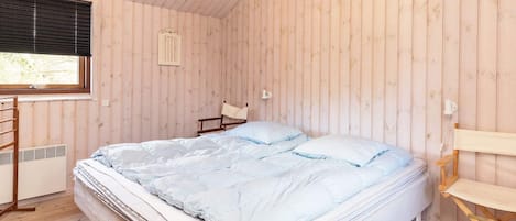 A room with a bed, a chair, a window, and a light fixture.