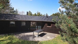 A modern house with a dark exterior, a sloped roof, and a patio area with a bench.