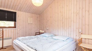 A room with a bed, a window, a chair, and a small table.