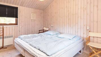 A room with a bed, a window, a chair, and a small table.