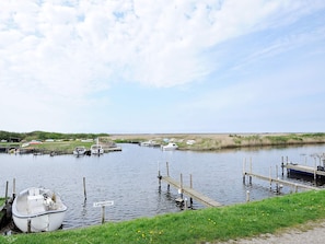 A calm waterway with boats docked at wooden piers, surrounded by grassy banks. - Picturesque Holiday Home in Ulfborg near Sea (Ulfborg)