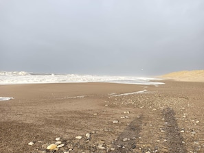 A beach with a pebbly shore and waves crashing onto the sand. - Picturesque Holiday Home in Ulfborg near Sea (Ulfborg)