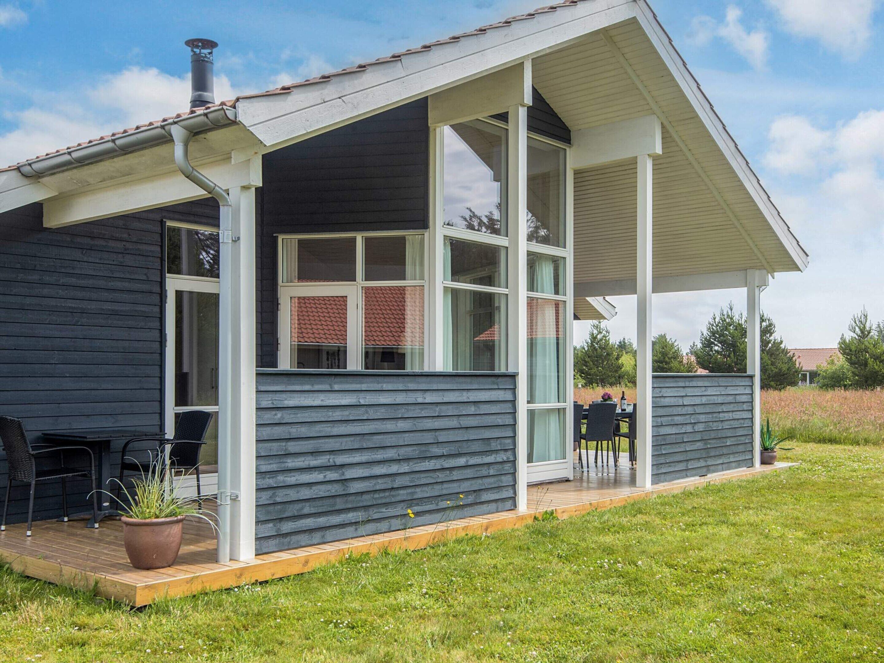 Une maison dotée d’un porche abrité, de grandes fenêtres et d’une cheminée.