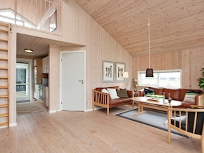 A spacious living area with a wooden floor, a sofa set, a dining table, and a kitchen visible through an open door. - Picturesque Holiday Home in Ulfborg near Sea (Ulfborg)