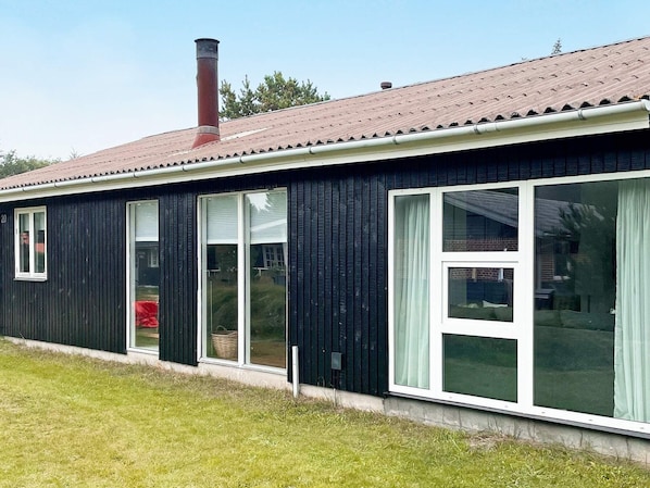 A single-story building with a dark exterior, a chimney, and large windows.