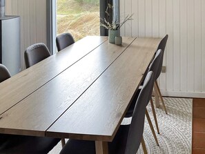 A dining area with a long wooden table, black chairs, and a small potted plant.