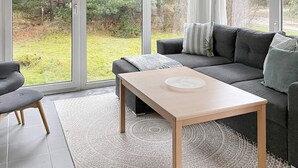 Ein modernes Wohnzimmer mit grauem Sofa, einem Holztisch und einem grauen Sessel.