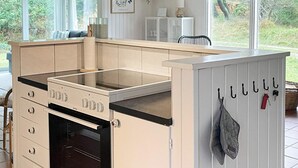 Eine kleine Küche mit Herd, Backofen und einem Schrank mit Haken.