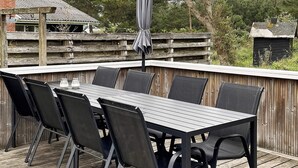 Eine Terrasse im Freien mit Holzdeck, einem rechteckigen Tisch und sechs Stühlen.