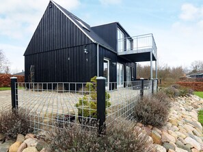 A modern black building with a metal fence, a stone pathway, and a small garden area.