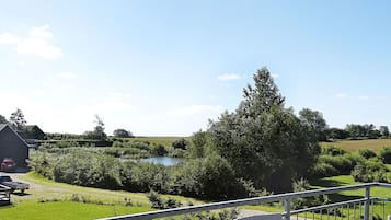 A rural landscape with a body of water, greenery, and a building.