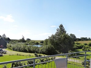 A rural landscape with a body of water, greenery, and a building.