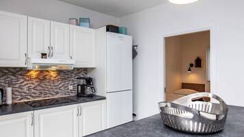 A modern kitchen with white cabinets, a black countertop, and a blue pendant light.