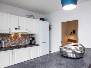 A modern kitchen with white cabinets, a black countertop, and a stainless steel colander.