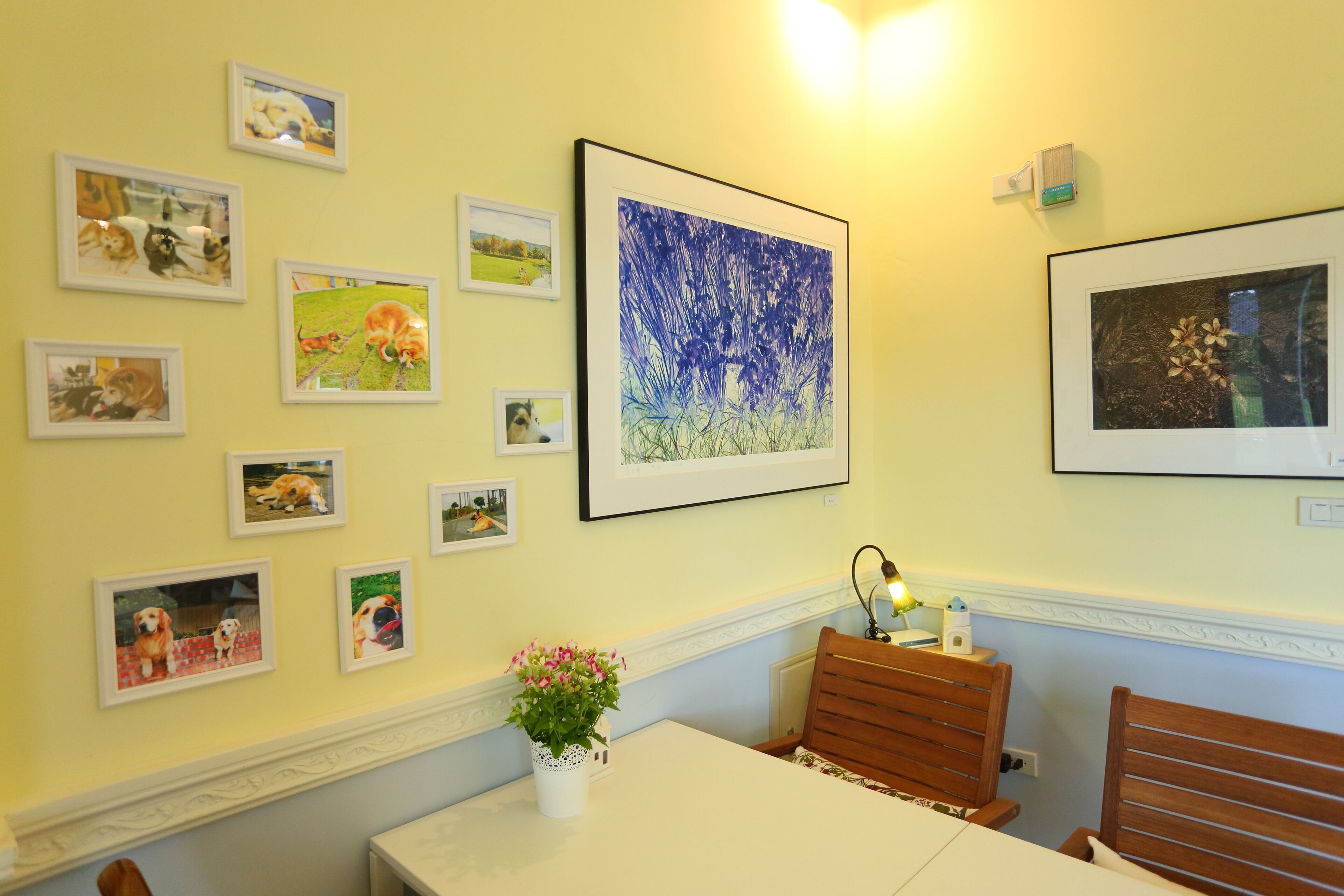 A dining area with a table, chairs, and a wall decorated with framed pictures.