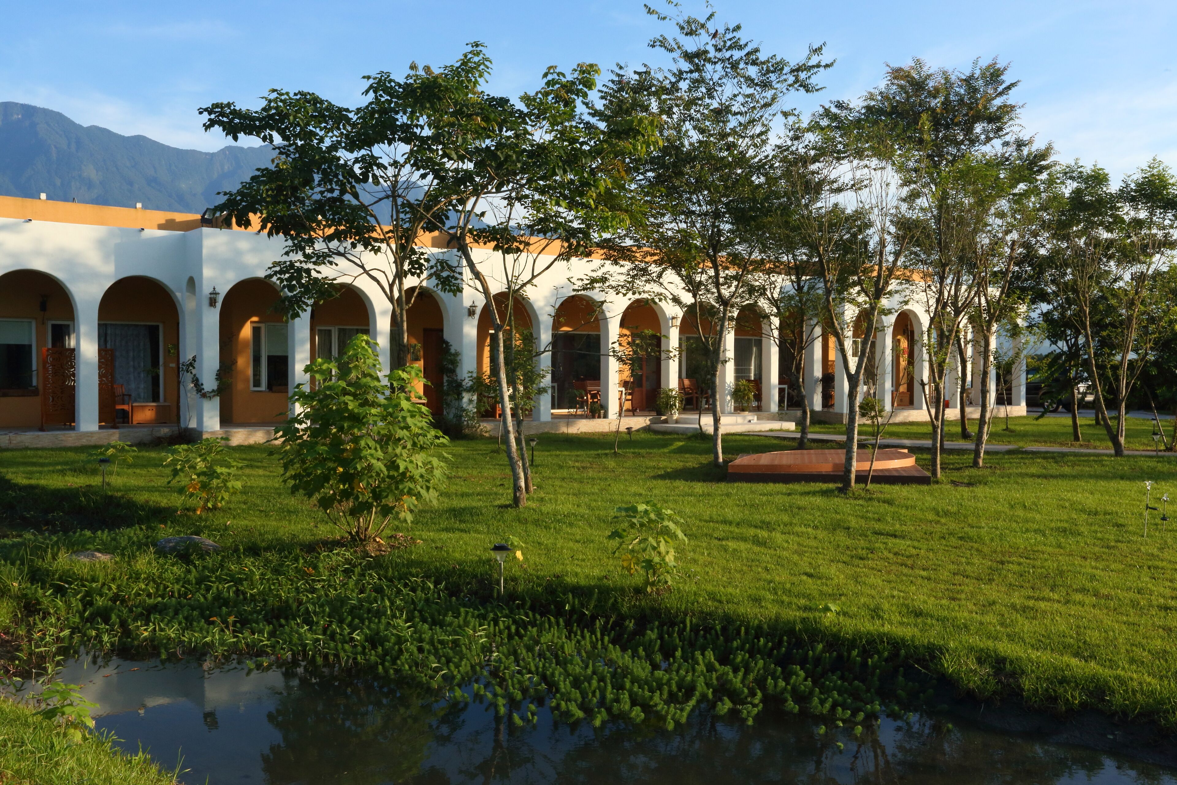 A courtyard with a pool, surrounded by a building with arched windows and a white facade.