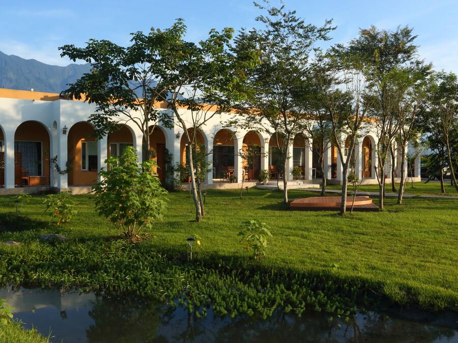 A courtyard with a pool, surrounded by a building with arched windows and a white facade.