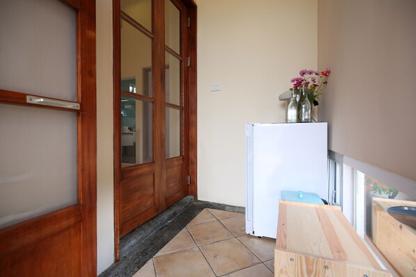 Una cocina con refrigerador, gabinetes de madera y una ventana con flores.
