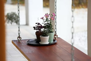 A wooden bench with a tray holding two potted plants and a metal bowl.