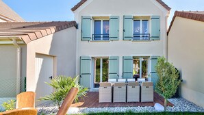 A two-story house with a balcony, a patio with outdoor furniture, and a small garden area. - MickeyRelax Luxury Spa Villa near Disneyland Paris (Villeneuve-Le-Comte)