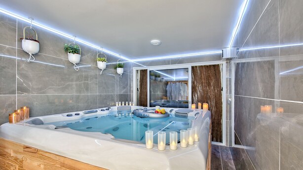 A modern spa area with a hot tub, candles, and potted plants. - MickeyRelax Luxury Spa Villa near Disneyland Paris (Villeneuve-Le-Comte)